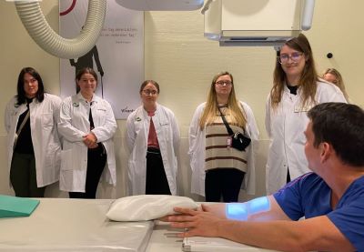 Students watch an instructor demonstrate elbow positioning in radiology room