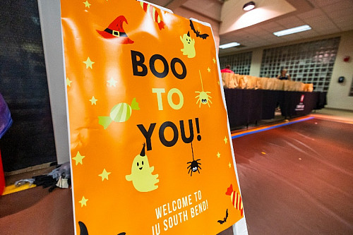 Orange sign with words Boo to You decorated with ghost and witch hat imagery.