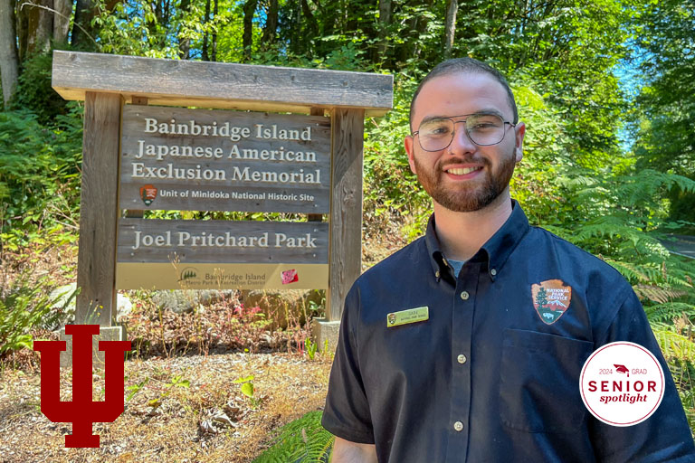 A man stands in front of a national parks sign