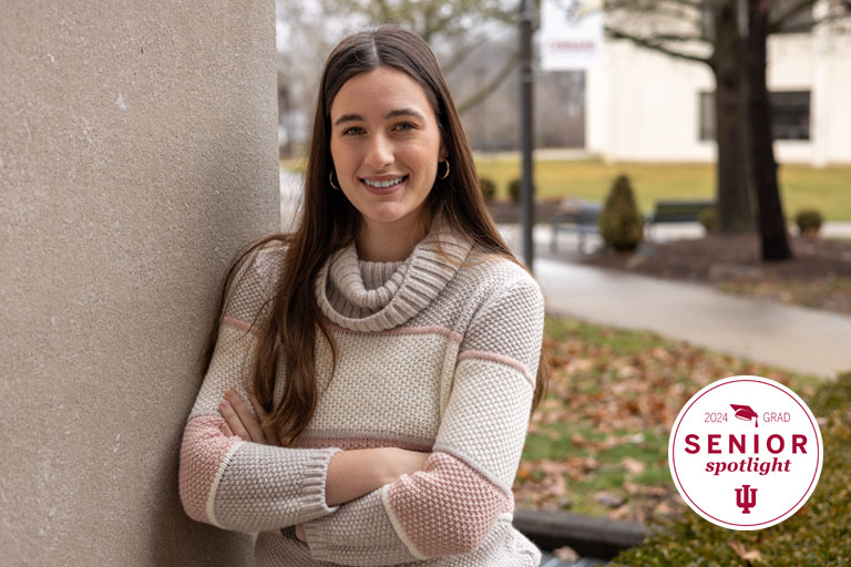 A woman poses next to a building