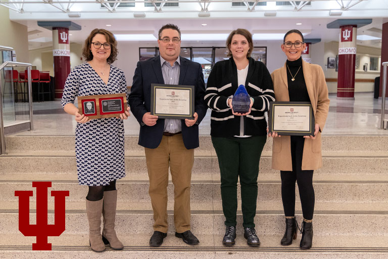 A row of people hold award certificates