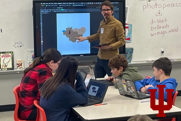 A man stands in front of a a screen in a classroom