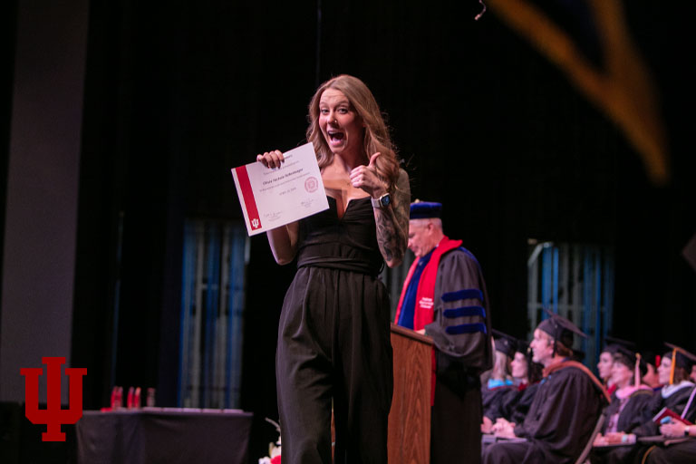 A woman on a stage holds a certificate