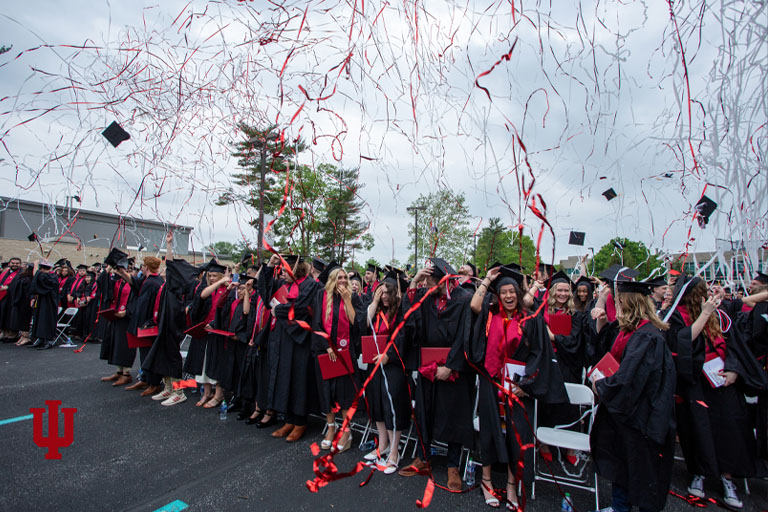 Graduates stand in rows with confetti