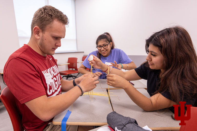 A man and two women build a structure