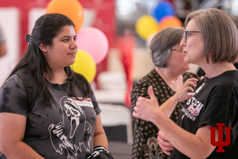Two women talk in front of balloons
