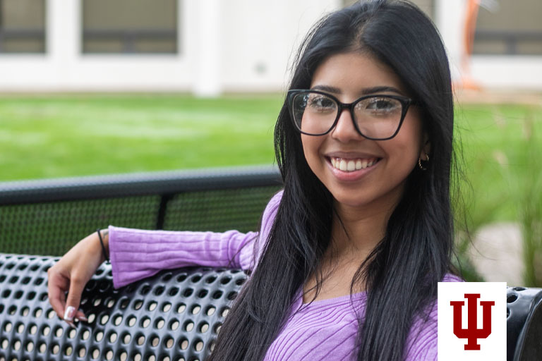A woman in a purple sweater sits on a bench