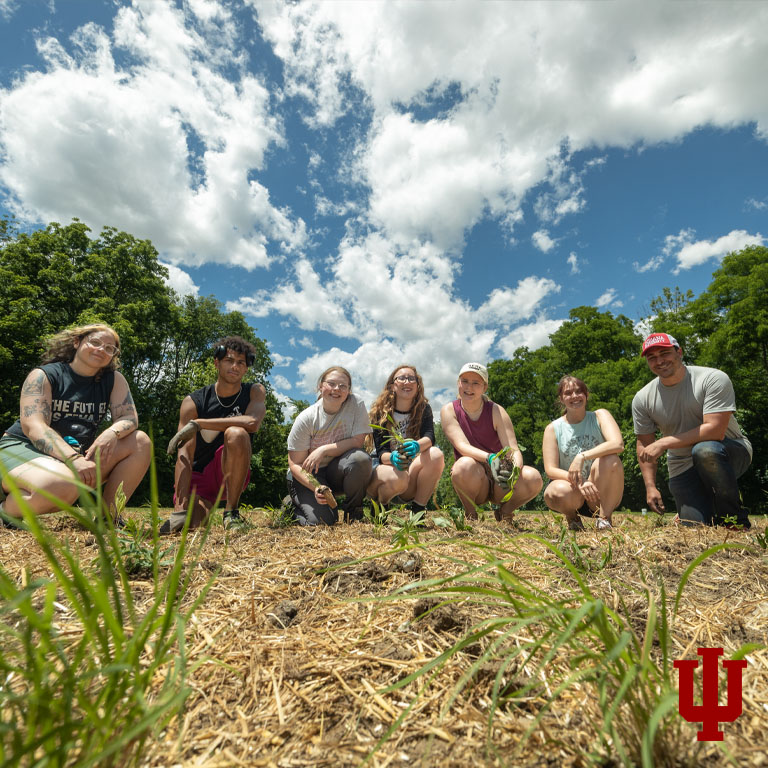 Seven people pose in a garden