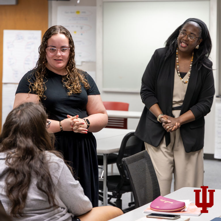 Three women talk in a classroom