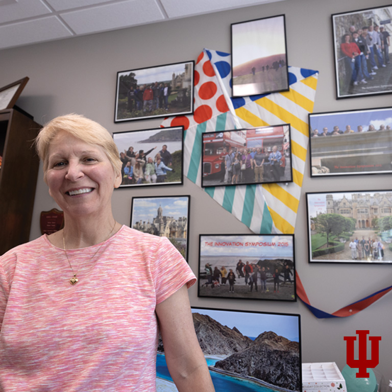 A woman stands in front of a wall of pictures