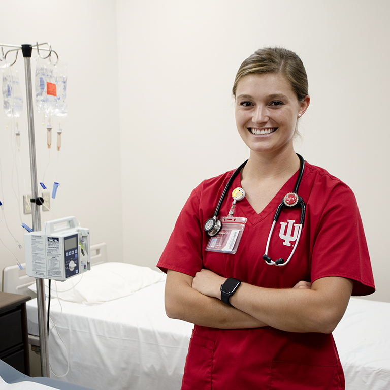 A woman poses in red scrubs