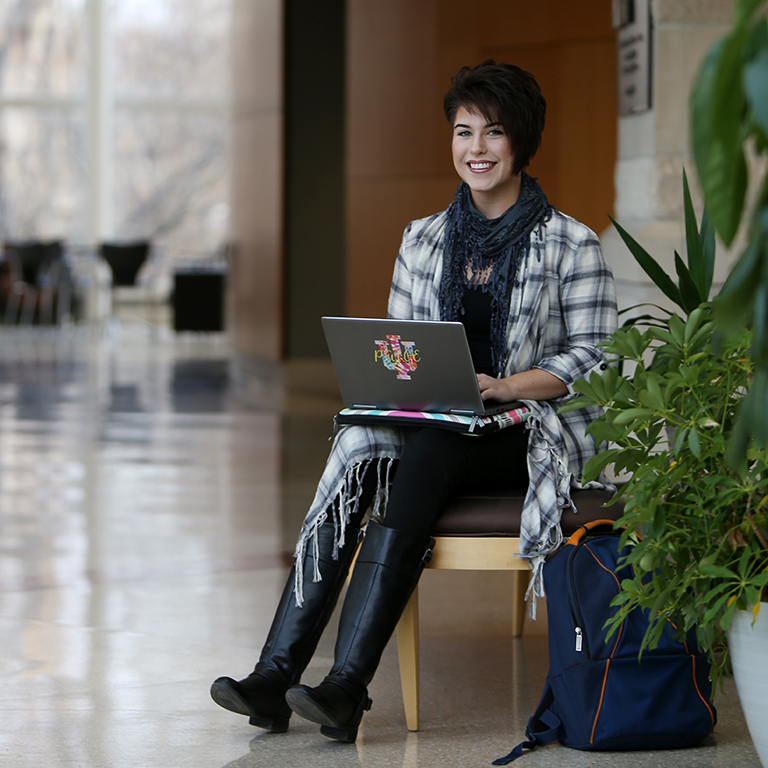 A woman sits with a laptop