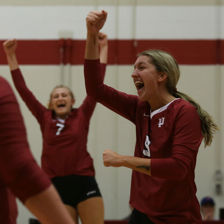 Two volleyball players in red cheer