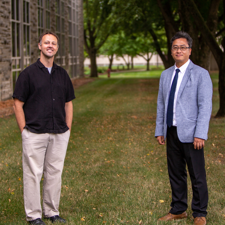 Two men stand by a tree