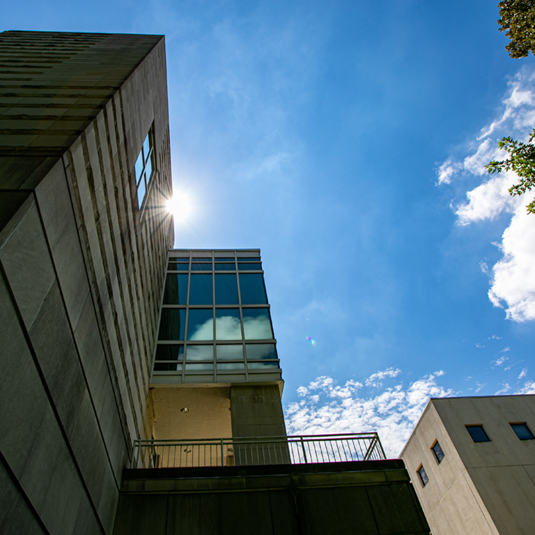 The sun peeks from behind a limestone building