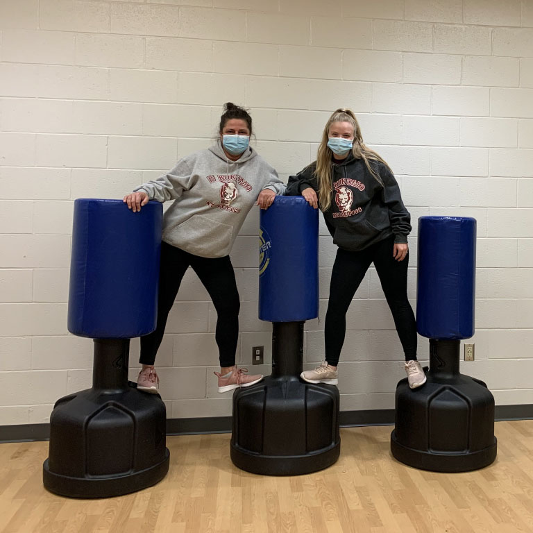 Two women pose with boxing bags