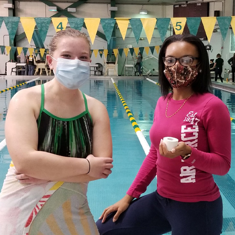 Two women stand in front of a swimming pool