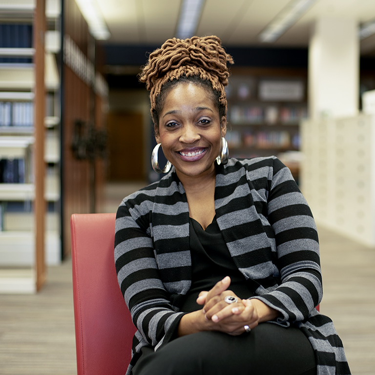 A woman sits on a chair in a library