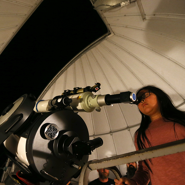 A person looks into a telescope.
