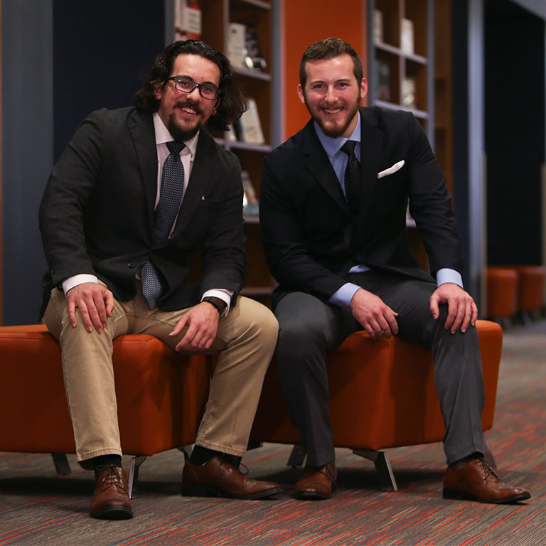 Two men in suits pose for a portrait