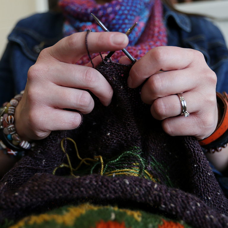 A woman's hands hold a piece of knitting in progress