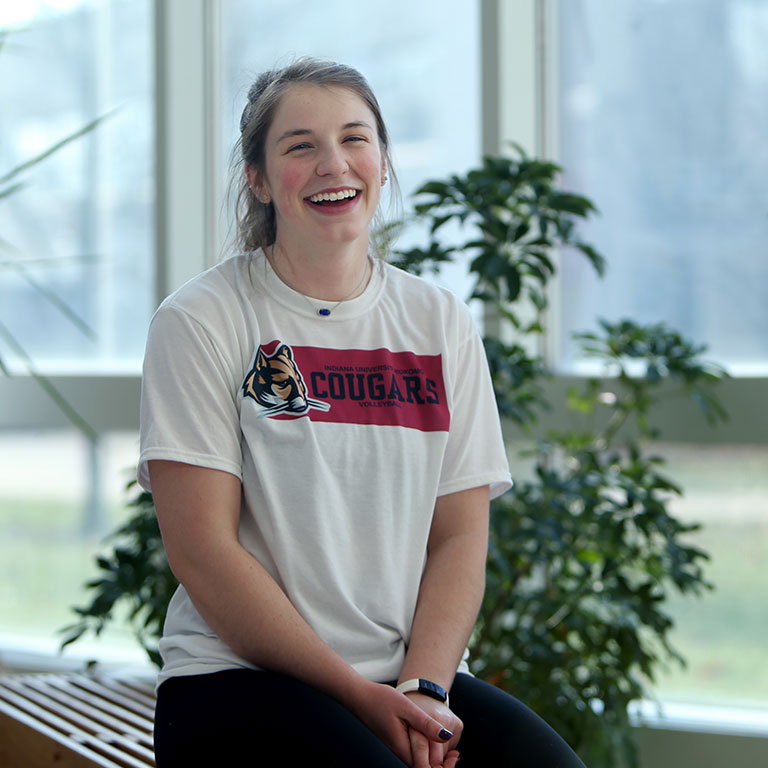 A smiling woman poses for a picture in an atrium