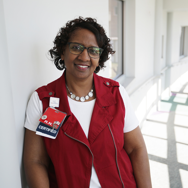 A woman wears a white shirt and red vest