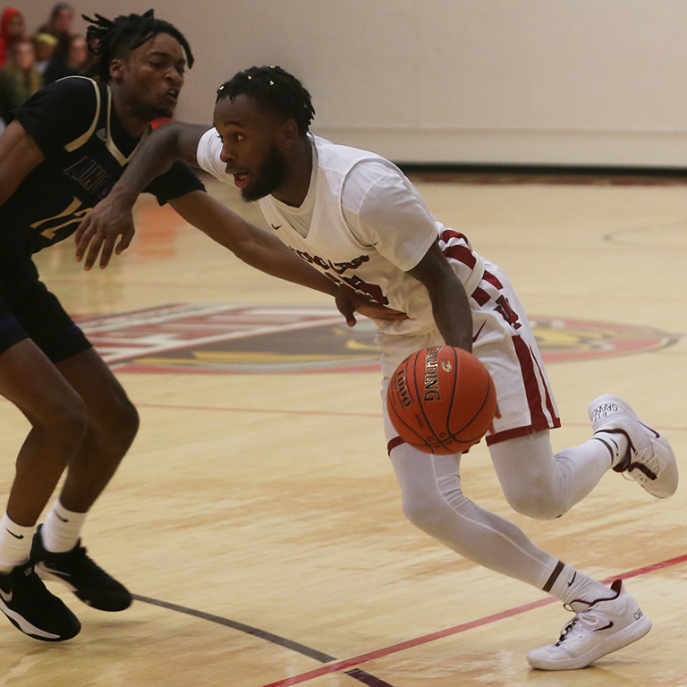 A man playing basketball defends against someone guarding him
