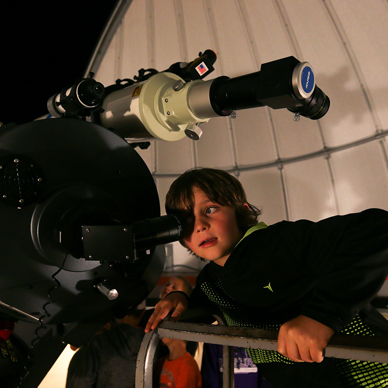 A child looks into a telescope