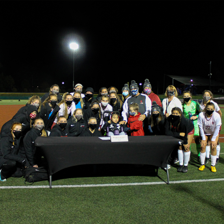 A team of women gather around a girl in a wheelchair