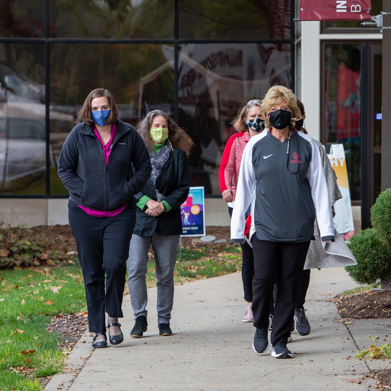 A group of five women walk out of a building.