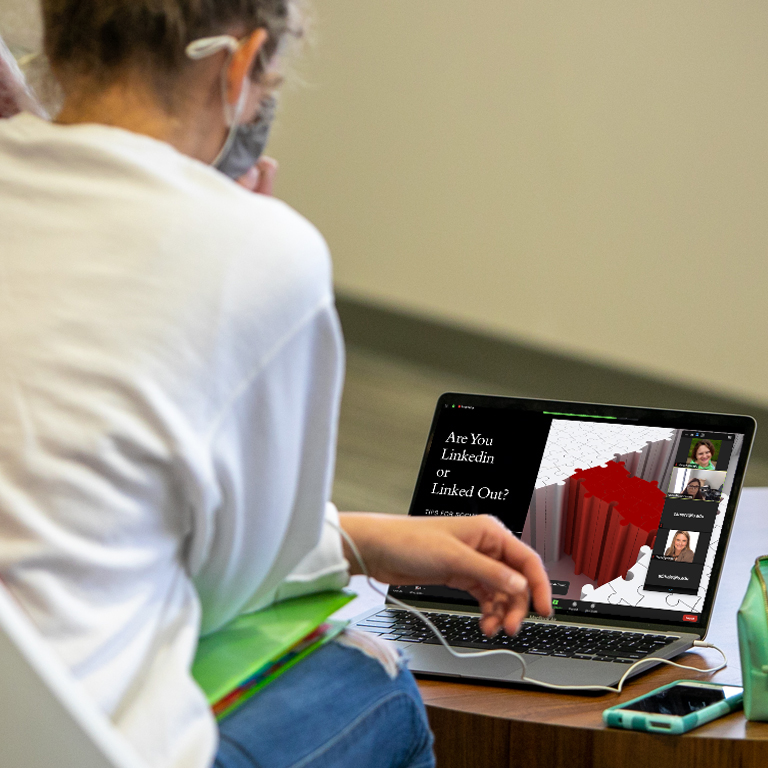A person looks at a Zoom meeting on a laptop