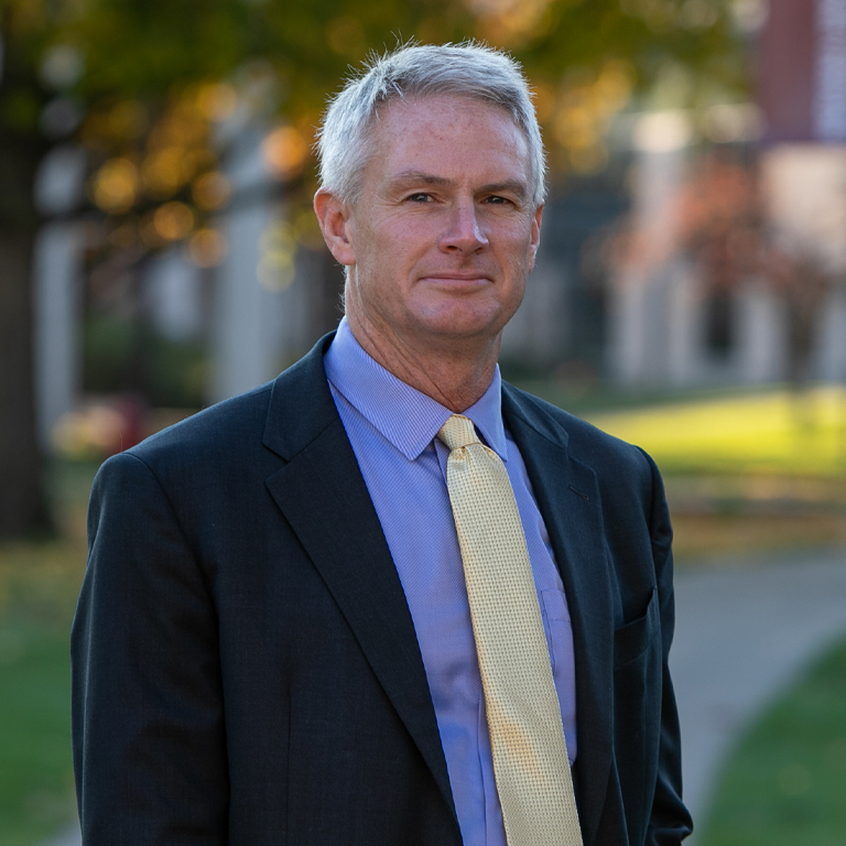 A man in a suit poses for a portrait