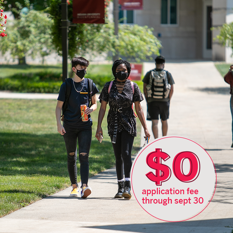 Three people in masks walk in the quad