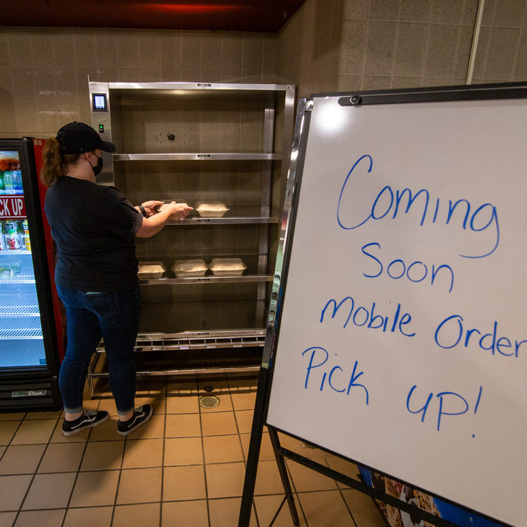 A woman puts food on a pick up station