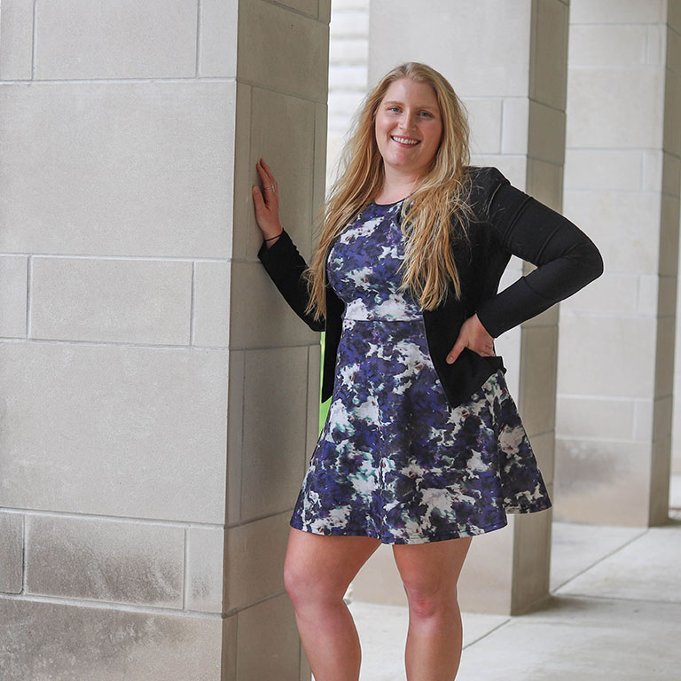 A woman stands by a limestone column