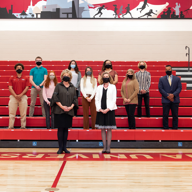 A group of masked people stand on bleachers