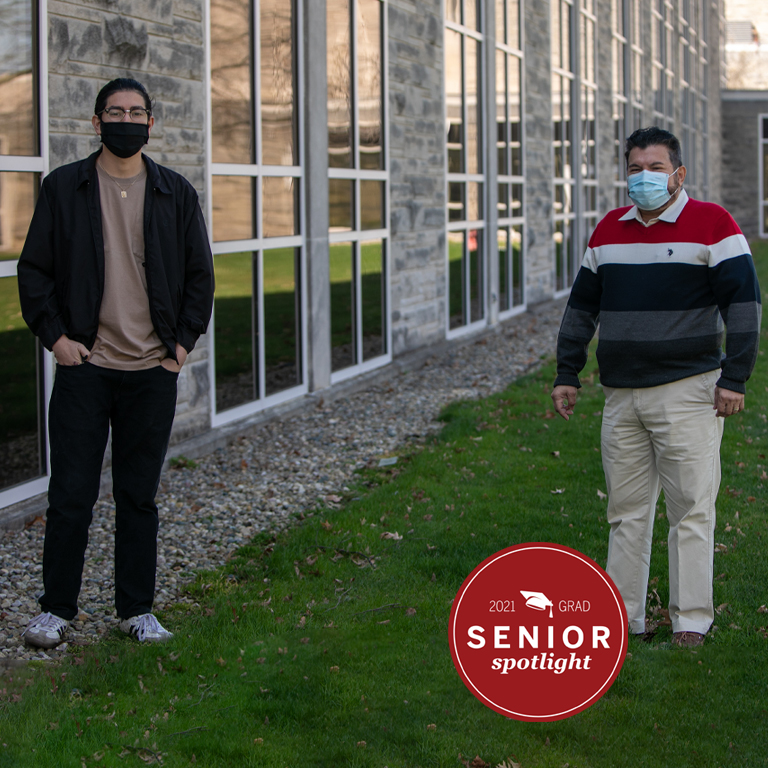 Two men in masks stand by a building