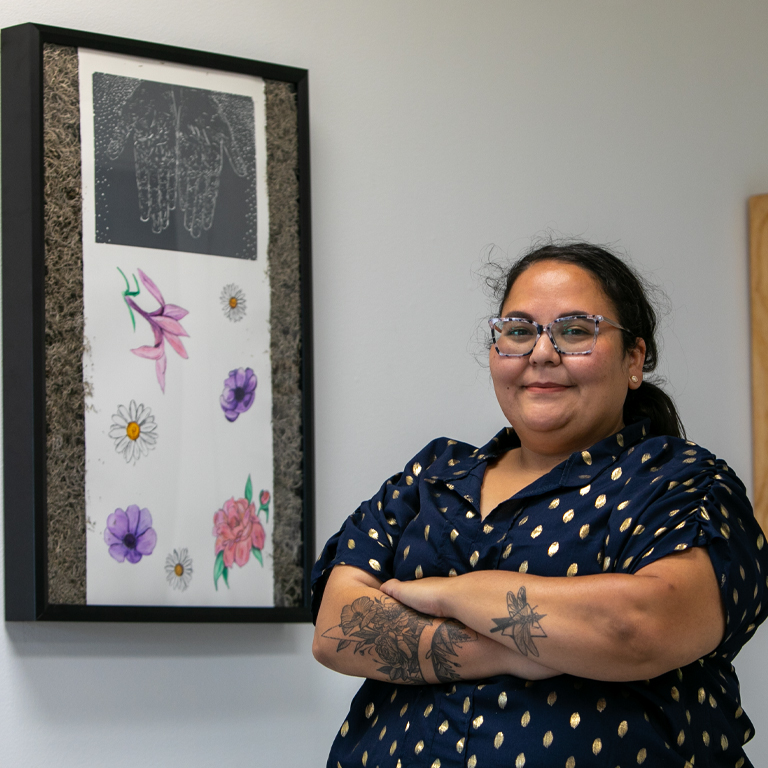 A woman stands by a piece of artwork