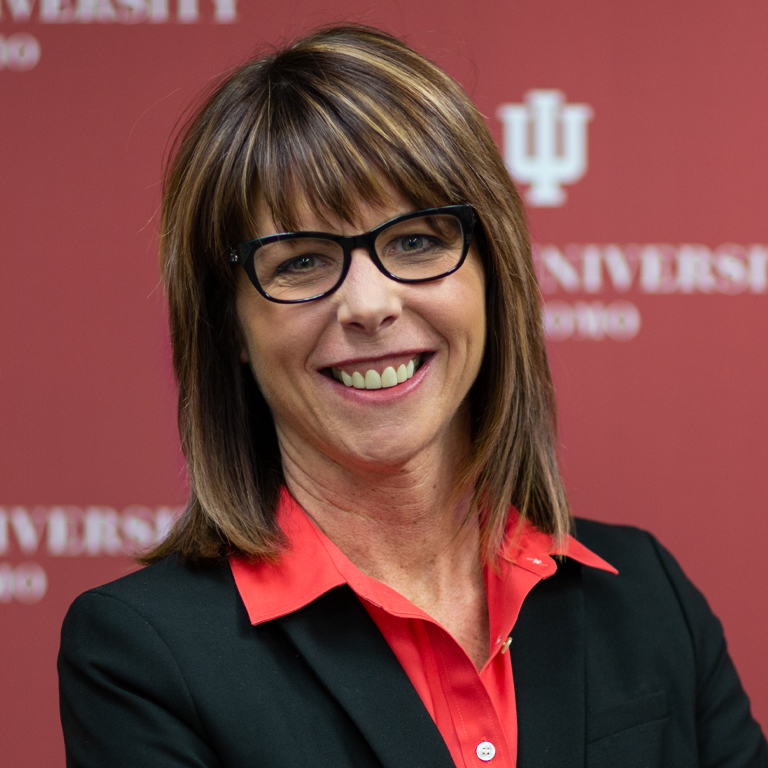 A woman poses in front of a red backdrop