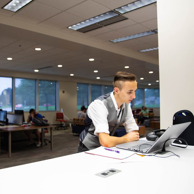 A person works at a laptop in the library