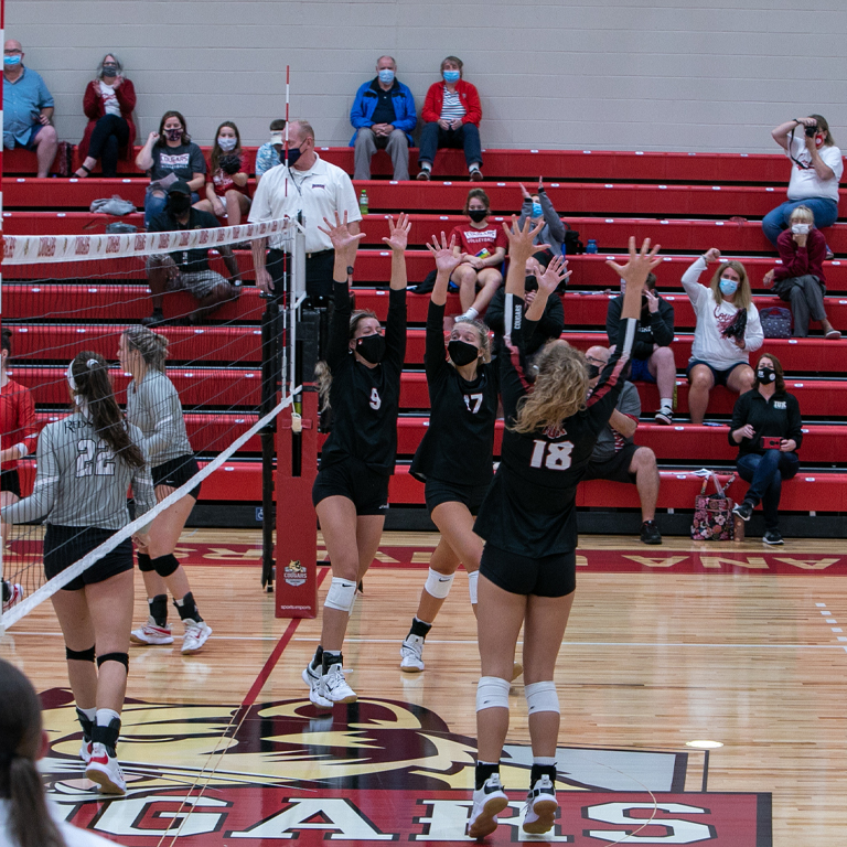 Three female volleyball players celebrate