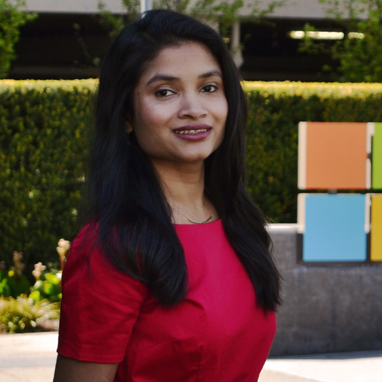 A woman stands in front of a Microsoft sign