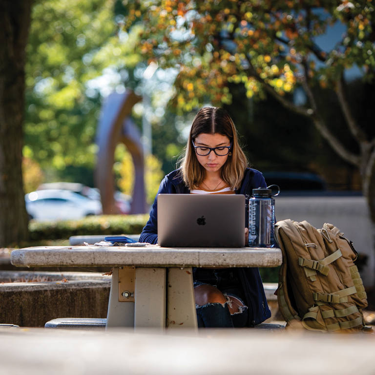 A woman studies at an outside table
