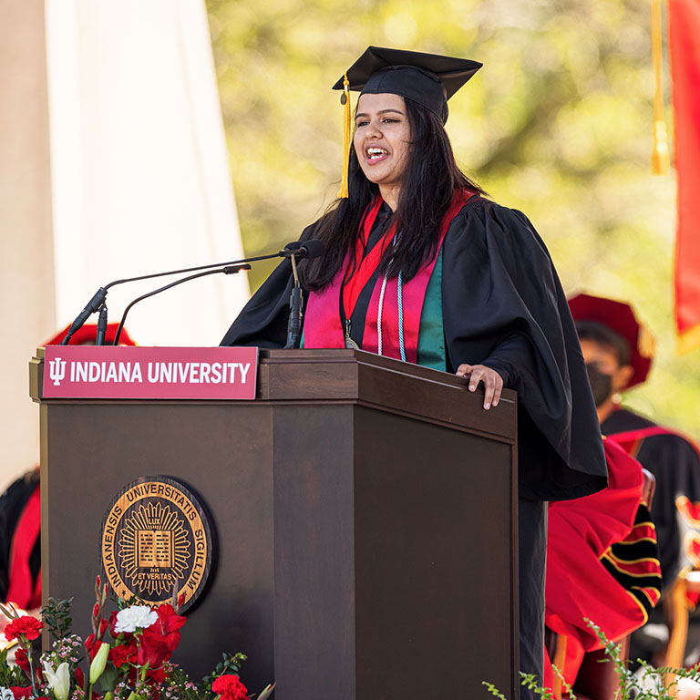 A woman in a cap and gown at a lectern