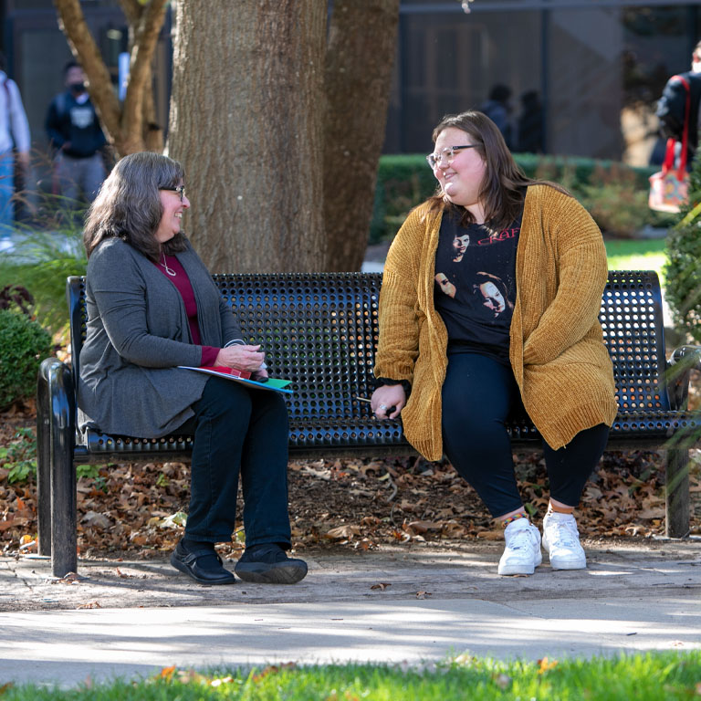 Two women sit on a bench