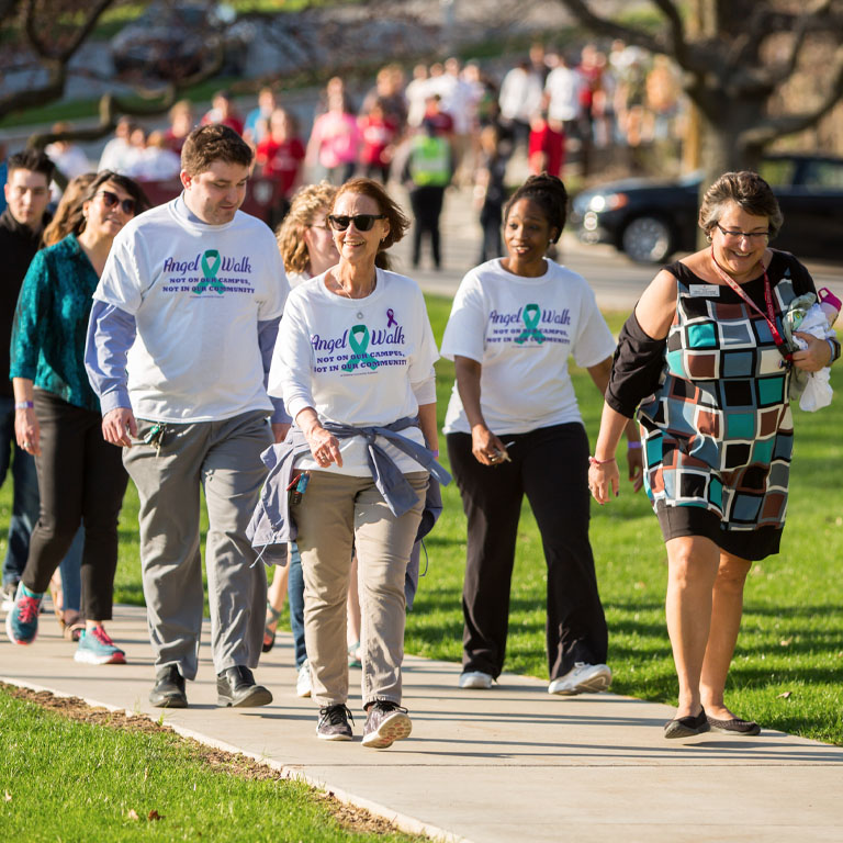 A line of people walk through campus