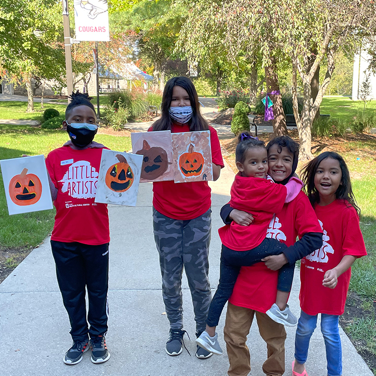 Five children in red Little Artist T-shirts hold up paintings