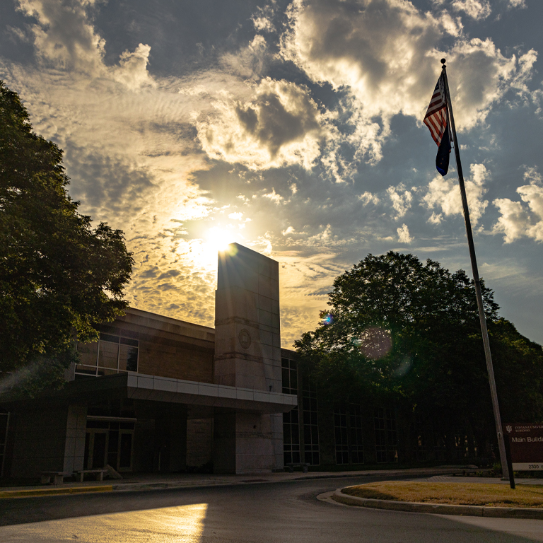flagpole in front of a limestone building at sunrise