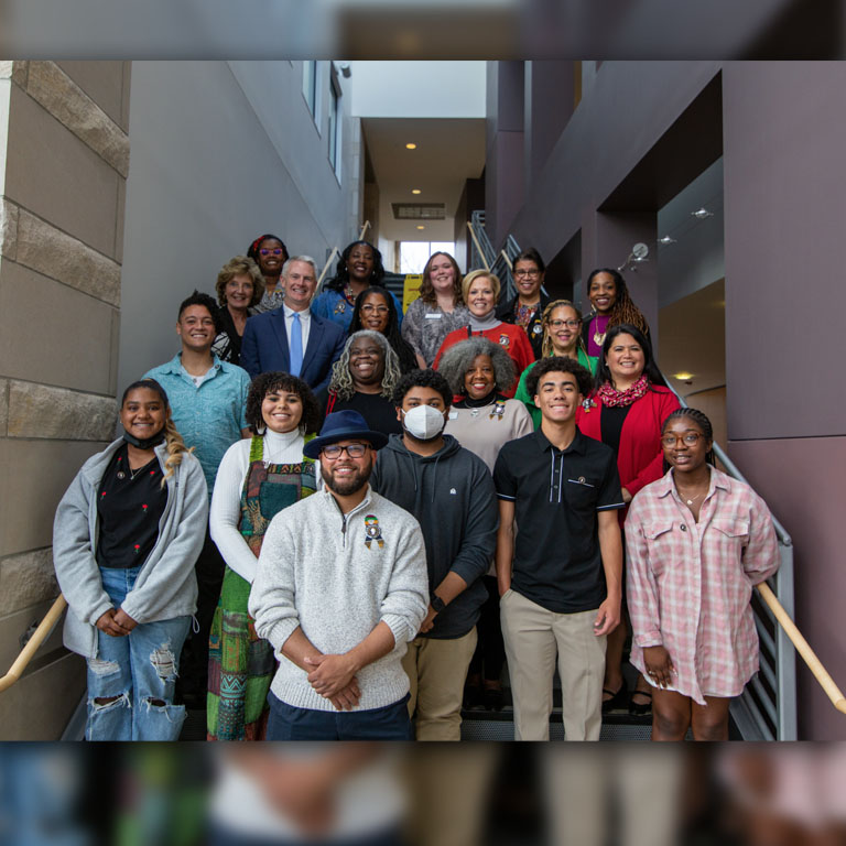 Five rows of people pose on a staircase.